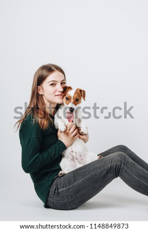 Studio portrait of young cute woman smiling and hugging her jack russell terrier dog. Love between owner and dog. Isolated on white background.