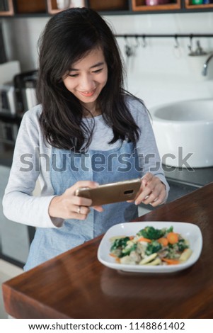 beautiful asian woman taking some picture of her cooking at home