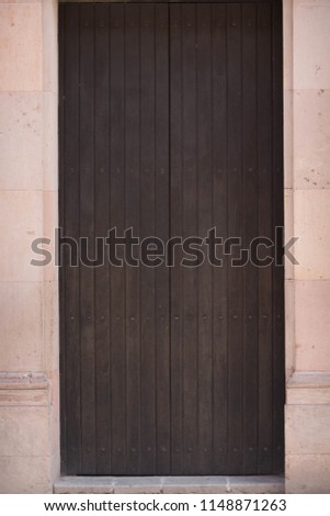 A black wooden door with a stone frame.