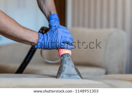 Closeup of upholstered Sofa chemical cleaning with professionally extraction method. Man is holding nozzle. Royalty-Free Stock Photo #1148951303