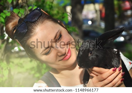smiling girl holding a black rabbit in hands