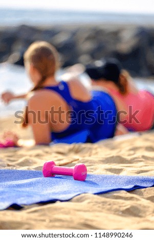 Pink Dumbbell on the background of women doing sports on the beach 