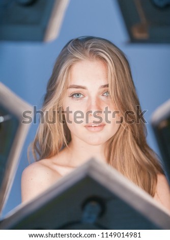 Beautiful young longhaired woman with star reflex in eyes and opened shoulders on blue background