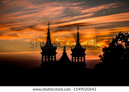 Silhouette bell towers of the Church of San Cristóbal against the sky during sunset, eclectic style, orange colors illuminating the horizon, wonderful spectacle of nature in Mazamitla Jalisco Mexico
