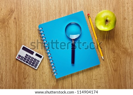 School accessories and apple on wood table