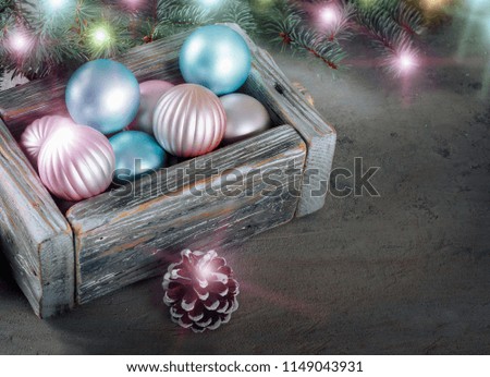Old wooden vintage box with beautiful pink and blue Christmas balls on  background with green fir branches and bright lights