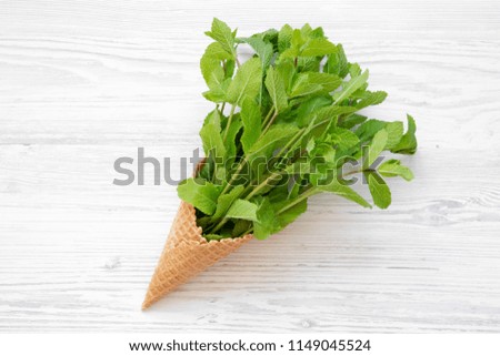 Waffle sweet ice cream cone with mint on white wooden table, from above. Top view, overhead.