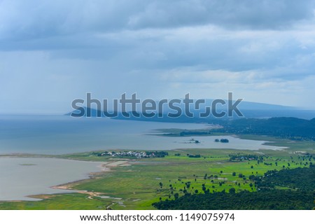 stormy cloudy sky over the national park lake and green plain below the viewpoint