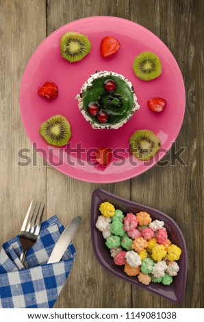 dessert cake with kiwi and strawberries on a wooden background. festive dessert on a plate top view