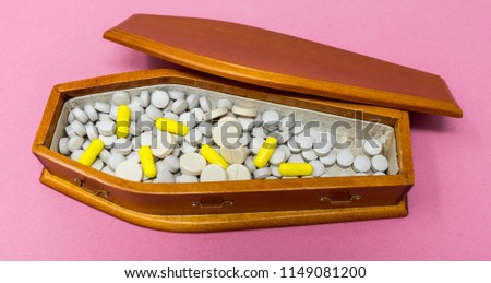 A wooden coffin full of gray round pills