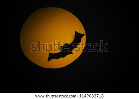The paper work, flying bat over orange full moon in the dark, giving sense of halloween.
