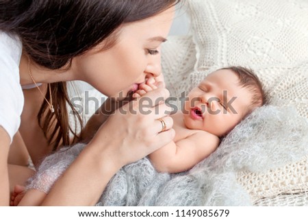 Pretty woman holding a newborn baby in her arms. Happy mother and her slipping newborn baby in the bed