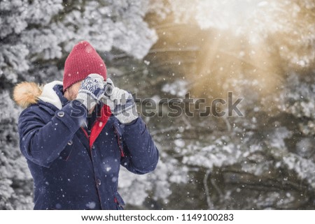 Fashionable man taking pictures with retro camera on snowy day. Winter vacation travel concept.