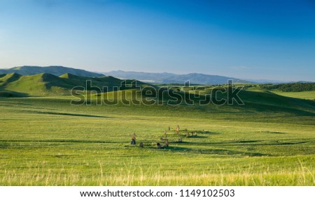 Distant hills. Hilly steppe. Curvy hills. Dolmens. Ancient gravestone. Blue sky and grass. Beautiful plain. Sunny day and hills. Lowland. Hilly horizon.  Royalty-Free Stock Photo #1149102503