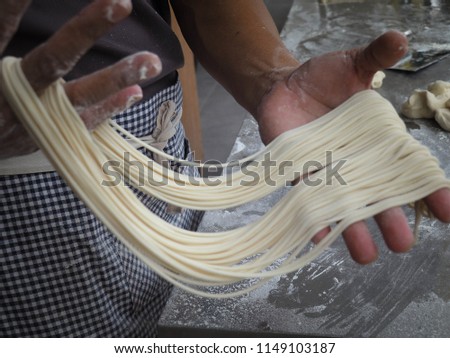 The dough is manually processed by hand to produce delicious pull noodles Royalty-Free Stock Photo #1149103187