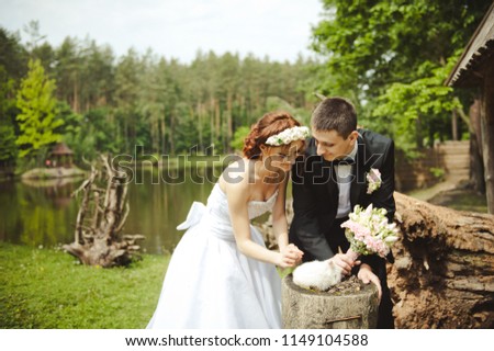 Groom and bride with a white rabbit. Happy wedding couple with rabbit