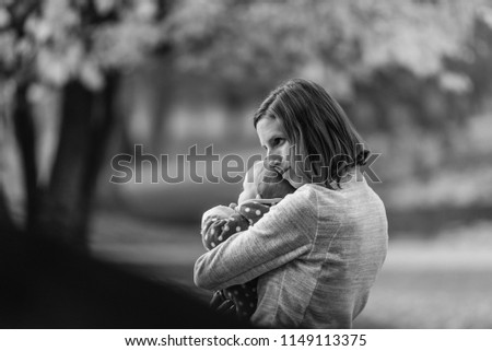 Black and white image of a happy mother hugging her baby girl outside in a park.