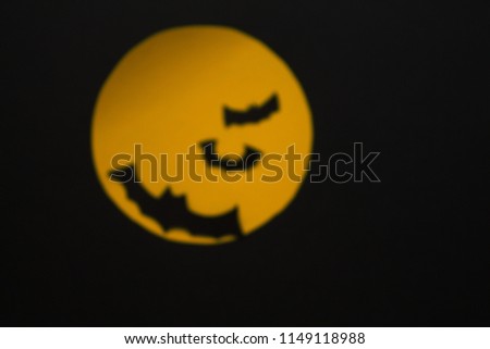 Intentional blurring image of the full moon with flying black bats. The composition composed to imply halloween tradition.
