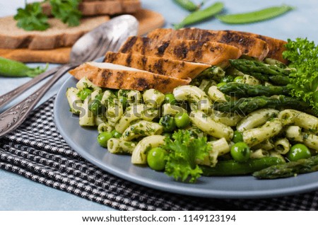 Pasta in green sauce with vegetables and meat. Selective focus.
