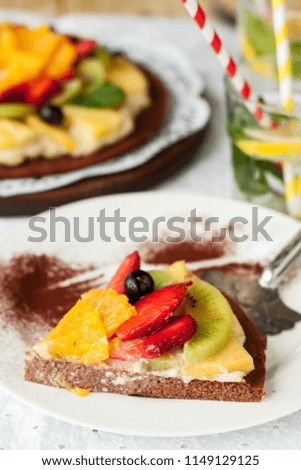 Healthy snack - fruit pizza with strawberry, pineapple, orange, kiwi and blueberry on white wooden table