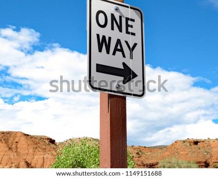 One Way Street Sign On A Small Desert Road With Red Rock And Blue Sky