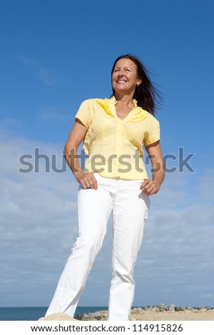 Portrait of relaxed and attractive looking senior woman enjoying active retirement and leisure time at sea, isolated with ocean and blue sky as background and copy space.