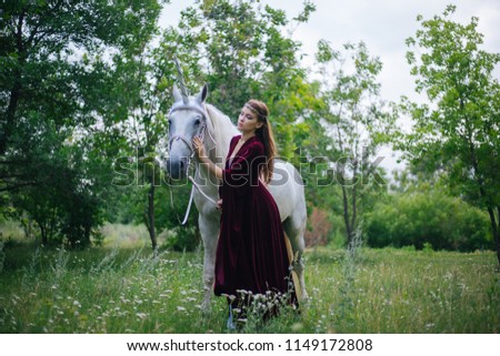 Beautiful girl in red medieval dress with unicorn. Fantasy. Woman Elf