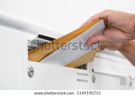 Close-up of a man's hand inserting letters in mailbox Royalty-Free Stock Photo #1149190715