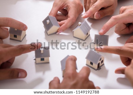 Group Of People Touching Miniature House On White Background Royalty-Free Stock Photo #1149192788