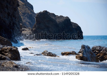 Rocky seashore with waves on a bright sunny day.