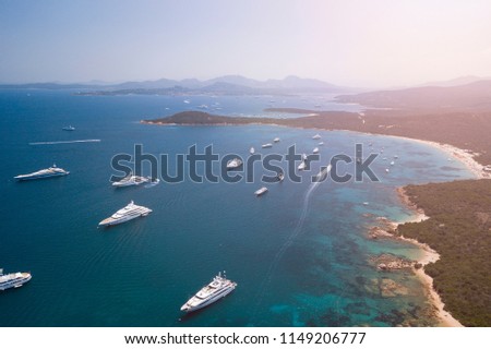 View from above, aerial picture of the amazing Emerald Coast with a turquoise and transparent Mediterranean sea full of luxury yachts and boats during the summer season, Sardinia, Italy.