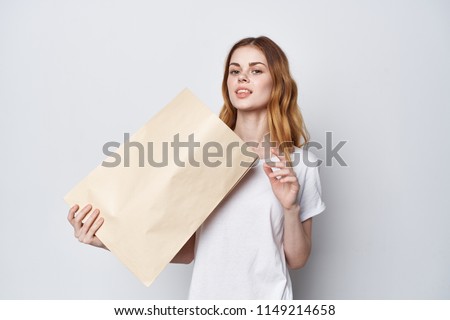  A woman in a white T-shirt is holding a packet in her hand.                              