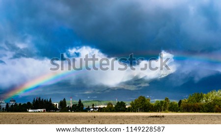 A rainbow appears among thick clouds below the Tatra mountains, Slovakia.