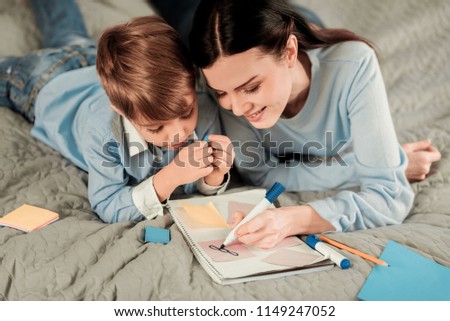 Beautiful picture. Nice young woman drawing while spending time together with her son