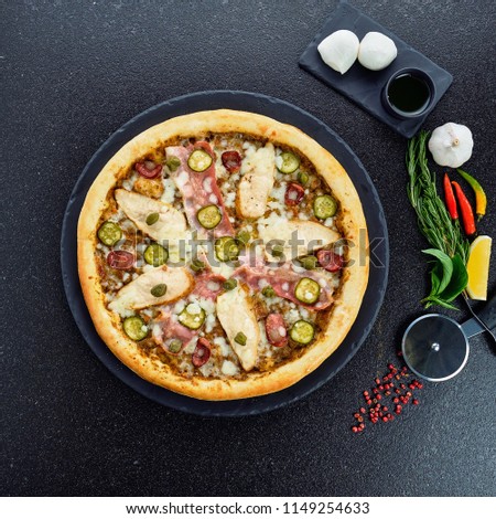 Meat Pizza with melted mozzarella cheese, chilli pepper and tomato on black stone background. Pizza menu.