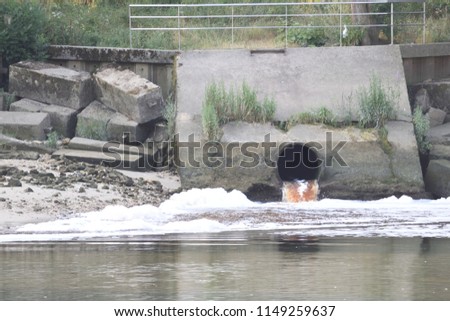 Waste water outlet on river with foam and pollution