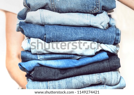 The girl holds a stack of jeans in her hands. cleaning in the closet.
