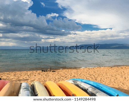 Colorful Kayaks on a beach with dramatic clouds and blue sky. 