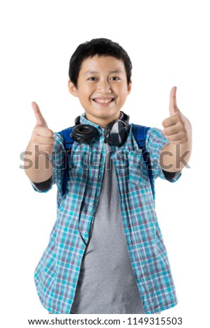 Picture of Asian preteen student looks happy while showing thumbs up and standing in the studio