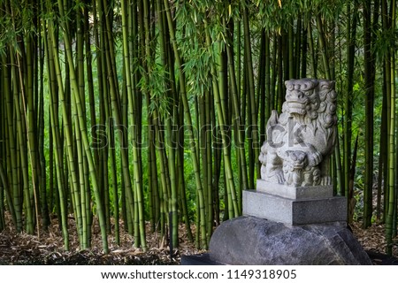 Traditional Shi Shi Dog or Shisa statue or Foo Dog - statue to ward off evil and protect in a bamboo garden.