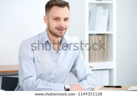 Portrait of businessman sitting at the desk in office workplace