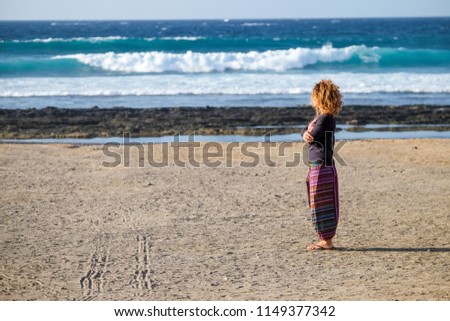 beautiful lonely caucasian middle age woman walk and enjoy the nobody beach in season. freedom and alternative lifestyle concept for independence lady feeling the ocean and nature