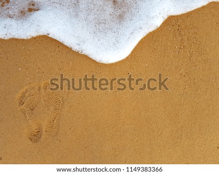 The footprints and waves foam on the beach sand, slow life and happiness life in summer holiday.
