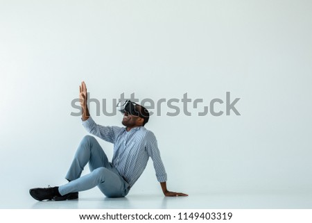 Exciting view. Cheerful afro american man sitting on the floor while testing vr glasses Royalty-Free Stock Photo #1149403319