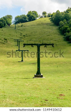 green country landscape with ski lift on green run slopes, shot in bright summer light at Cainallo Alp, Lecco, Lombardy, Italy
