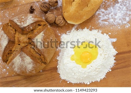 Egg yolk in flour next to many mixed breads on the wooden table, concept shot from above.