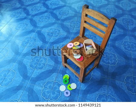 English lettering cards are placed on a wooden chair that is set on a glazed blue tile floor.