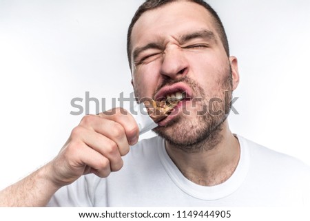 A close picture of guy eating sweet bar of chocolate with nouga. He is biting a big piece of this sweets. Young man is a fan of everythinf that is sweet. Isolated on white background.