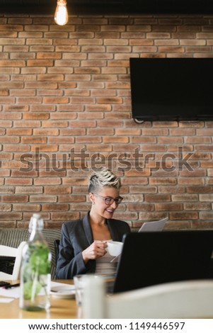 Young positive woman with glasses working in modern office.