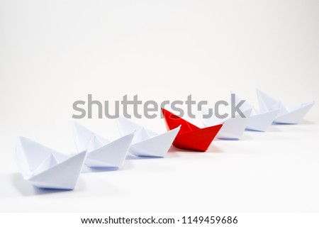 Red paper boat among white paper boat on white background. It is different color in the same thing which is different thinking concept.